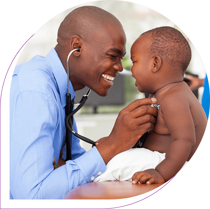 A doctor is holding a baby and smiling.